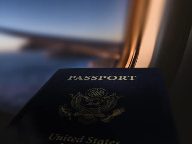 US passport resting on an airplane window ledge at sunset, highlighting Hainan's 30-day visa free entry for American travelers.