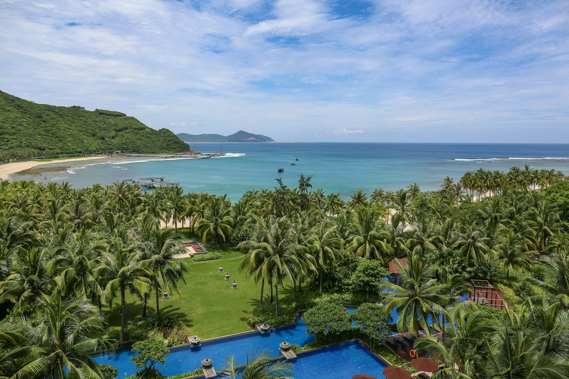 Tropical coconut palm trees lining the turquoise shoreline of Hainan Island, China's southernmost province.
