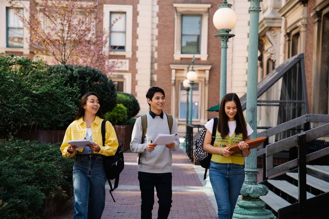 International students walking on university campus holding documents and notebooks