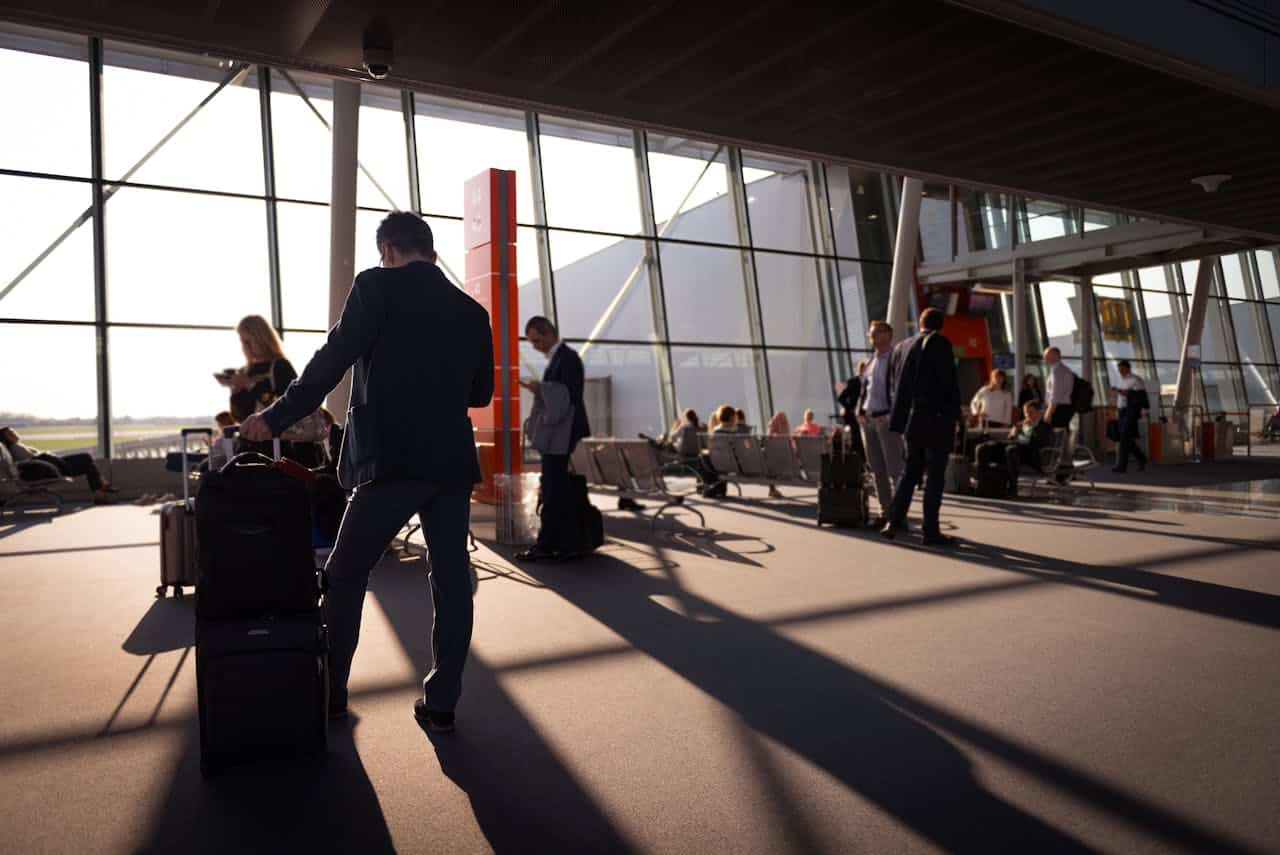 International business travelers moving through a busy airport terminal with carry-on luggage, representing the visa-free entry process for foreign professionals visiting China.