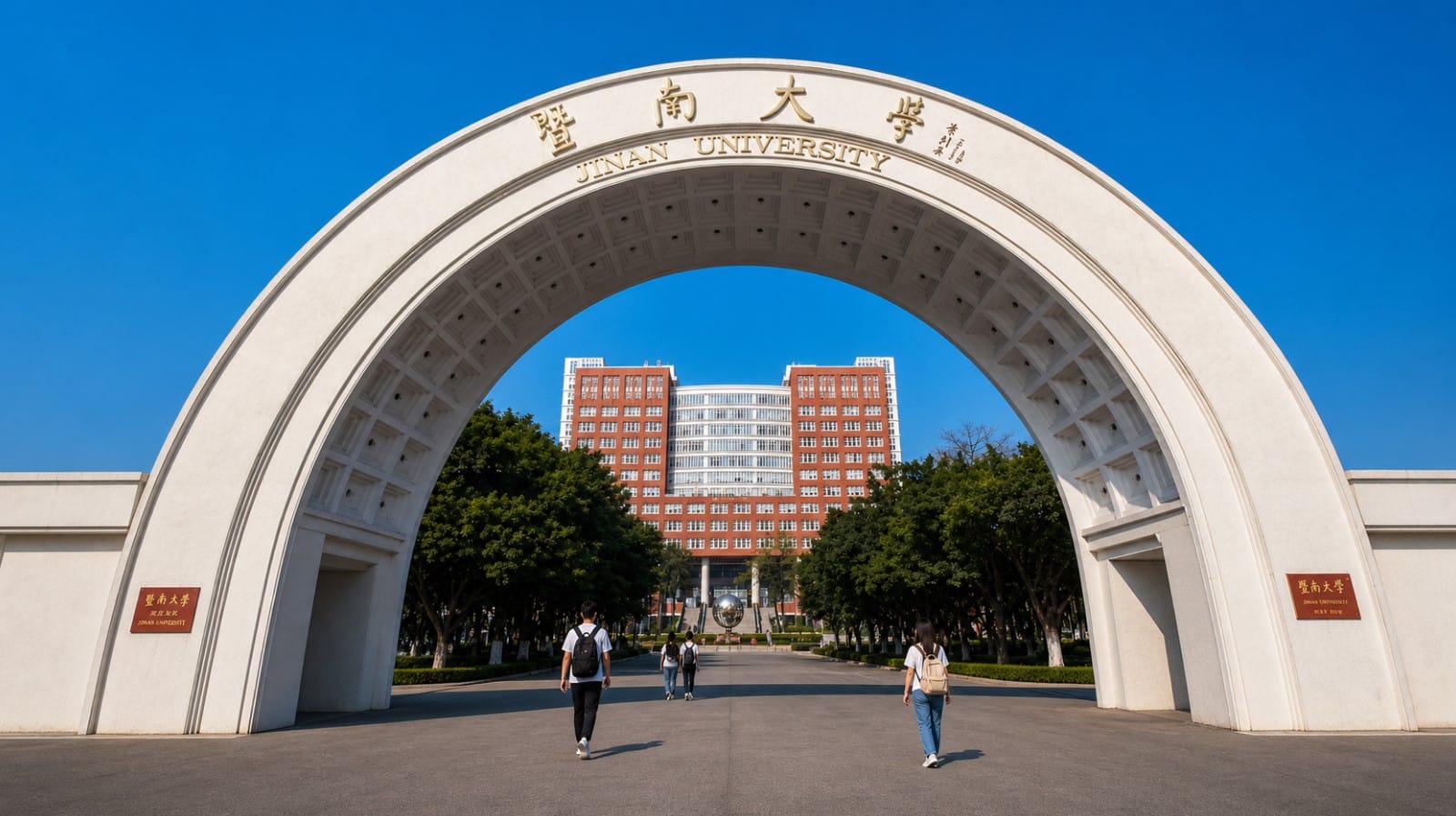 Jinan University main gate arch in Guangzhou with students walking toward the campus main building under a clear blue sky
