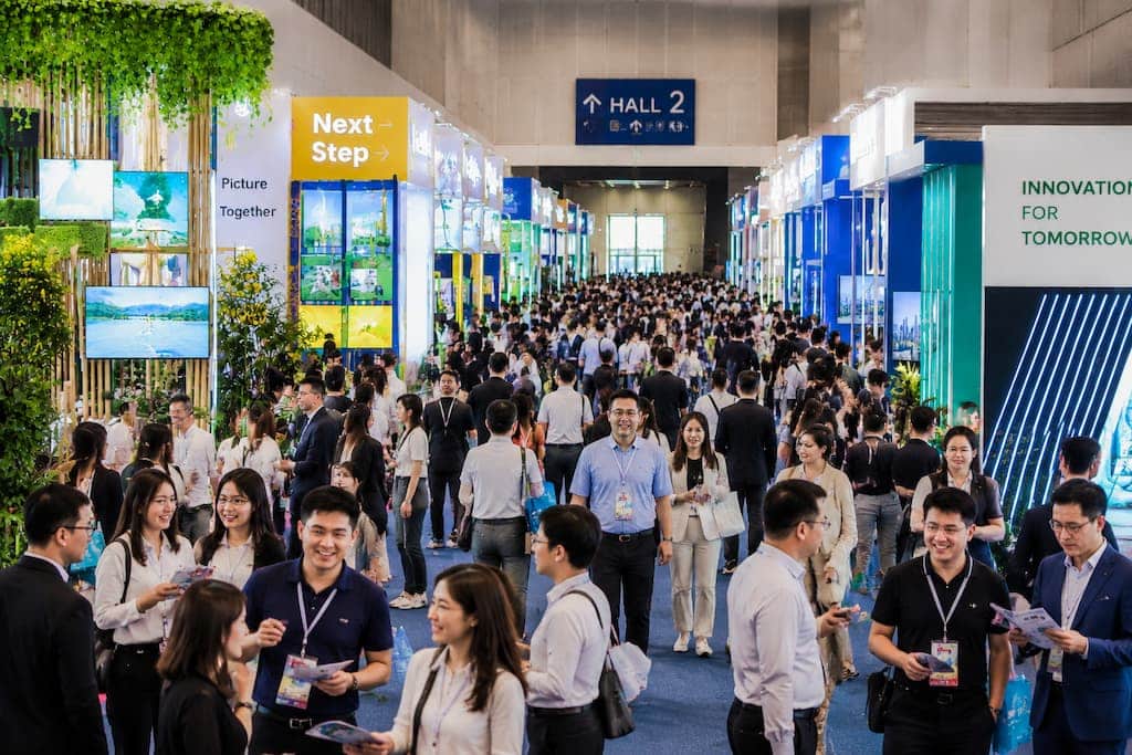 High-resolution panoramic view of ITB China 2026, showing a bustling convention hall with colorful exhibition booths, digital displays, and attendees networking and exploring the event.