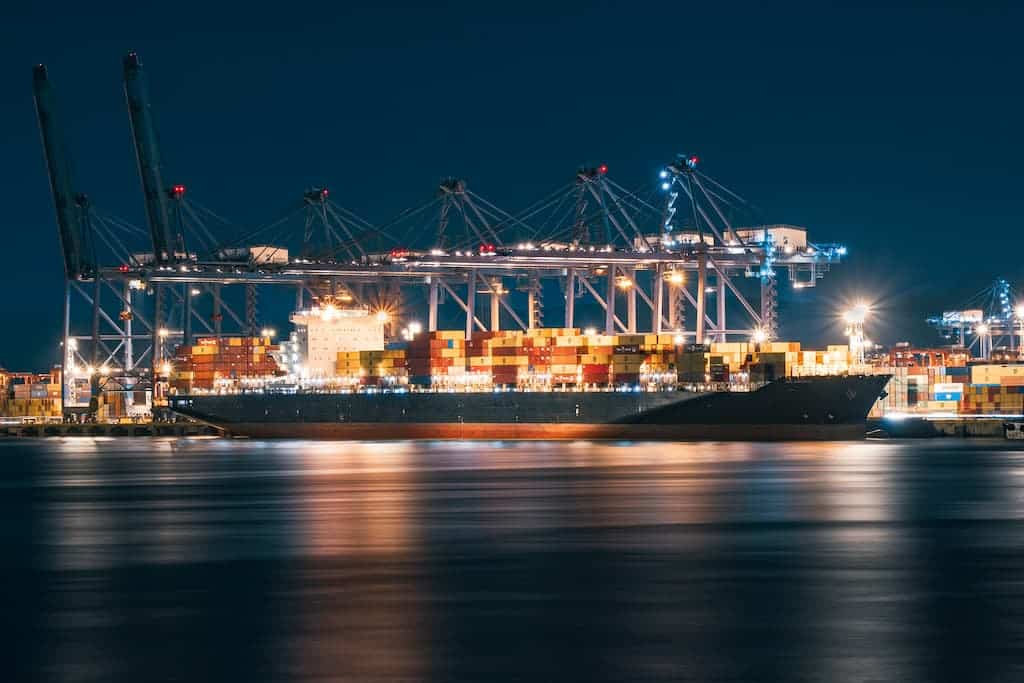 Cargo ship docked at a busy port at night representing the US-China trade truce extended agreement