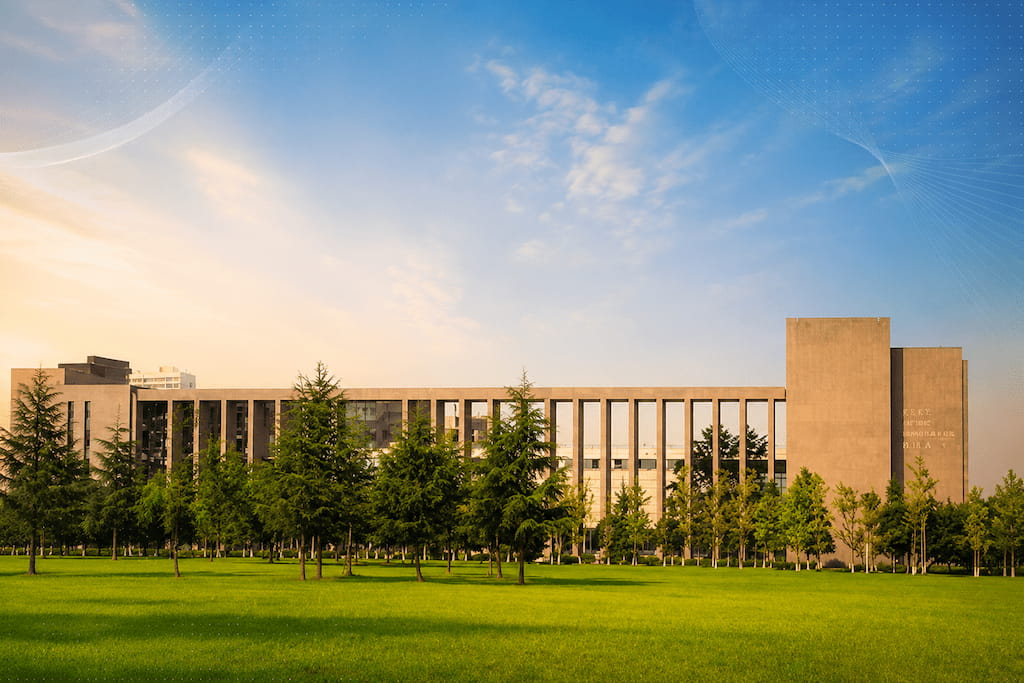 Colonnaded sandstone library building of Southwest Jiaotong University behind a green lawn and trees at sunrise