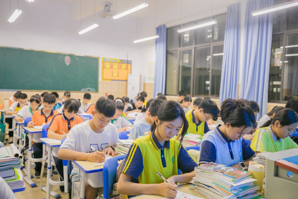 Chinese high school students in uniform studying at desks piled with textbooks during evening gaokao preparation