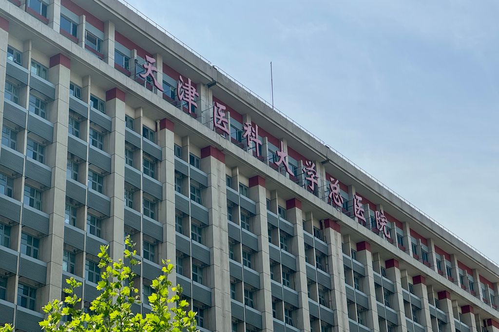 Facade of Tianjin Medical University General Hospital with red Chinese characters along the rooftop under a blue sky